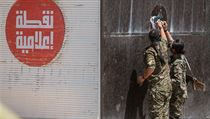 Kurdští vojáci strhávají plakát Islámského státu.