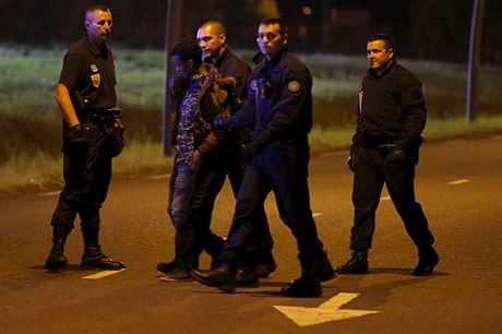 Francouzská poádková policie odvádí migranta, který se pokusil proniknout do...