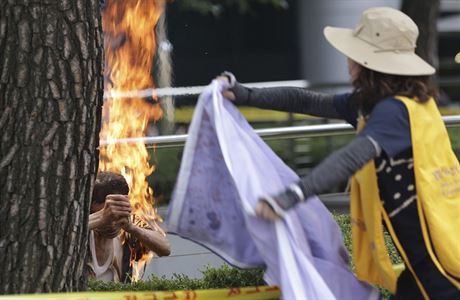 Úastnice protestu se snaí uhasit mue, který se zapálil na protest proti...