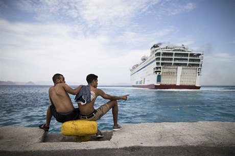 Migranti sledují píjezd trajektu k eckému ostrovu Kos.