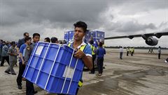 Pracovníci vynáejí balíky s humanitární pomocí pro lidi, které postihla...
