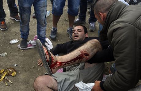 Zrann migrant le na zemi po stetech s makedonskmi policisty.