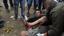 Zrann migrant le na zemi po stetech s makedonskmi policisty.