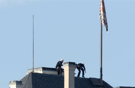Aktivisté, pevleení za kominíky lezou po stee Praského hradu, aby...