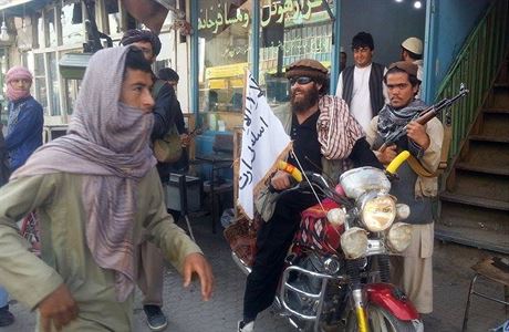 Bojovnk Talibanu na motocyklu s vlajkou radiklnho hnut ve mst Kunduz.