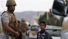 Jemenský chlapec vedle vojáka koalice vedené Saudskou Arábií, který drží hlídku...