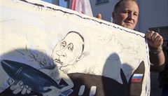 Vladimir Putin (na transparentu demonstranta karikován s ruským vojenským...