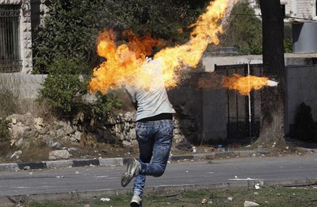 Palestinec hází Molotovv koktejl na izraelské jednotky pi stetech v Hebronu.