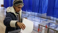 Žena hází do urny volební lístek ve volební místnosti v Kyjevě.
