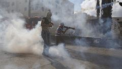 Palestintí protestující hází zpátky na izraelské vojáky slzný plyn.