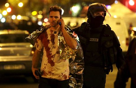 Francouzský policista odvádí zkrvaveného mue od koncertního sálu Bataclán.