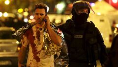 Francouzský policista odvádí zkrvaveného muže od koncertního sálu Bataclán.