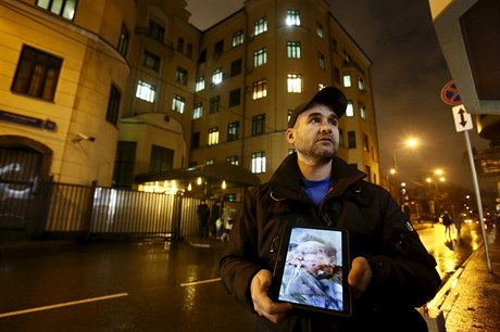 Ruský aktivista, který drží v ruce tablet s fotografií mrtvého pilota ruské...