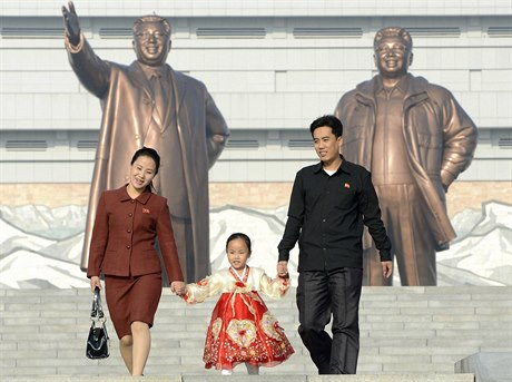 Severokorejská rodina. Na pozadí usmvavé sochy Kim Ir-sena a Kim ong-ila