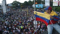 Stoupenec venezuelské opozice se státní vlajkou na pouličním shromáždění k...