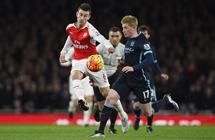 Kevin de Bruyne (vpravo) z Manchesteru City v souboji s Laurentem Koscielnym z...