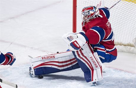 Branká Montréal Canadiens padá po zákroku útoníka  týmu Carolina Hurricanes.