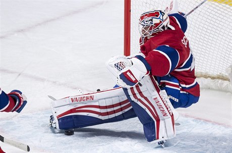 Brankář Montréal Canadiens padá po zákroku útočníka  týmu Carolina Hurricanes.