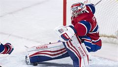 Branká Montréal Canadiens padá po zákroku útoníka  týmu Carolina Hurricanes.