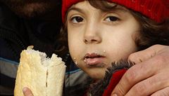 Malá uprchlice v objetí píbuzného sytí hlad chlebem v tranzitním stedisku pro...