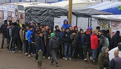 Migranti v táboe v Calais stojí frontu na distribuované obleení.