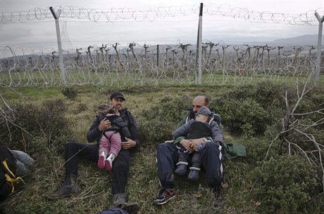 Migranti s dtmi v náruí odpoívají u pohraniního plotu severn od eckého...