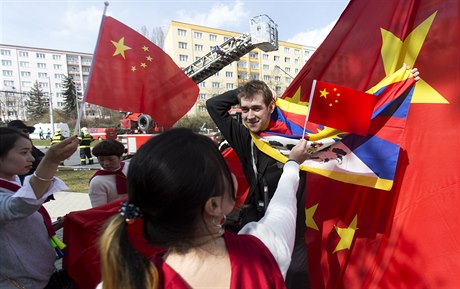 Protestující muž překrývá čínskou vlajku tibetskou.