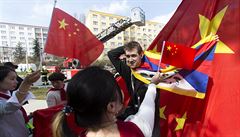 Protestující muž překrývá čínskou vlajku tibetskou.