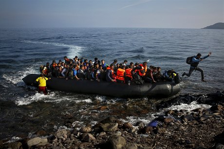 Afghánský uprchlík vyskakuje z přeplněného člunu na břeh ostrova Lesbos.