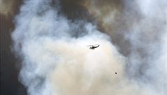 Maliká helikoptéra proti obím oblakm dýmu.