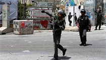 Izraelský policista hází granát se slzným plynem směrem k palestinským...