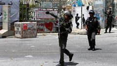 Izraelský policista hází granát se slzným plynem smrem k palestinským...