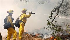 CalFire firefighters spray water on a controlled back fire while battling the...