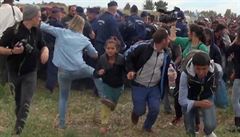 Maarská kameramanka (v modrém) podráí nohy mladé migrantce.