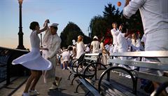 Lidé v bílém bavící se na písn tajném venkovním veírku Diner en Blanc.