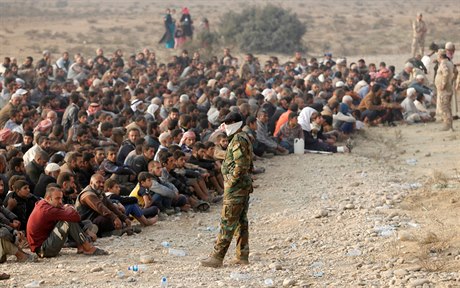 Irácký voják stojí ped skupinou pemístných civilist v Qayyae nedaleko...