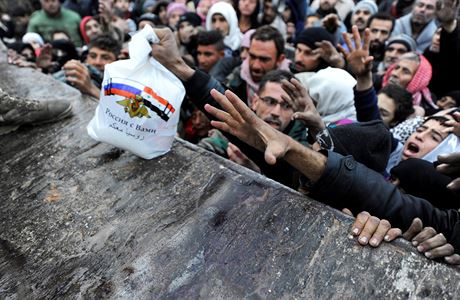 Syané uprchlí z Aleppa se natahují po ruském balíku s jídlem.
