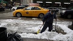A man sweeps the street after snow fell in Manhattan, New York City