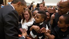 Prezident Barack Obama si tese rukou s malým chlapcem bhem akce poádané...