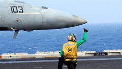 len posádky americké letadlové lodi dává signál pilotovi stíhaky F18...