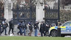 Ozbrojení policejní dstojníci vstupují do budovy parlamentu v Londýn.