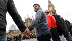 Lidé se drí za ruce na Westminster Bridge bhem vzpomínkové akce, která se...