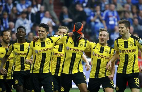 Fotbalisté Dortmundu slaví gól v síti Schalke, s maskou stelec Aubameyang.