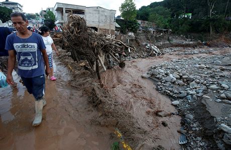 People walk in a destroyed area after heavy rains caused several rivers to...