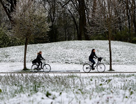 Cyklisté projídjí zasnenou loukou v Eichenau  v Nmecku