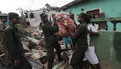 Sri Lankan army soldiers and rescue workers salvage belongings after houses are...