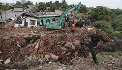 Sri Lankan army soldiers and rescue workers stand near buried houses in a...