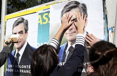 Voliky konzervativce Francoise Fillona vylepují na ulici jeho plakáty.