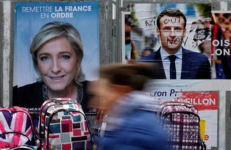 Žena prochází kolem plakátů Marine Le Penové a Emmanuela Macrona.