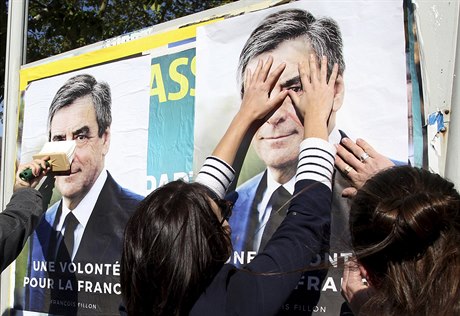 Voliky konzervativce Francoise Fillona vylepují na ulici jeho plakáty.